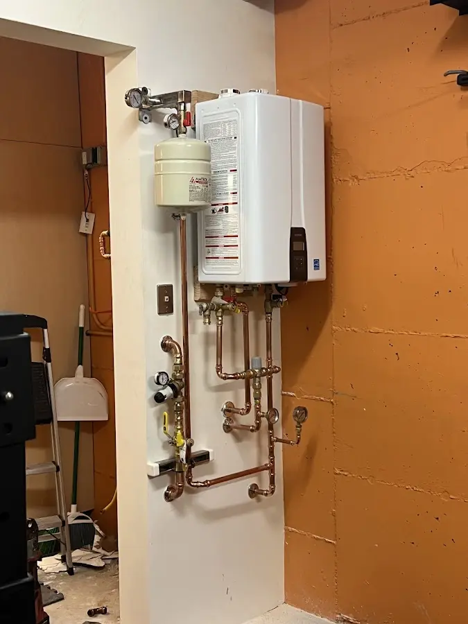 Plumbing technician inspecting water heater connections in East Fishkill